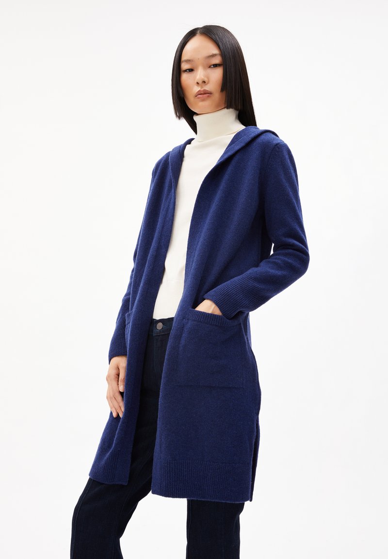 Navy Strickjacke mit Kapuze, gerippten Bündchen und zwei vorderen Taschen. Weicher Stoff, lange Ärmel und offenes Design.