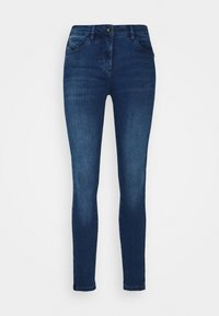 Los jeans skinny azul oscuro presentan una textura de denim suave, cinco bolsillos y un cierre de botón. El diseño incluye un ajuste clásico con un ligero desgaste.