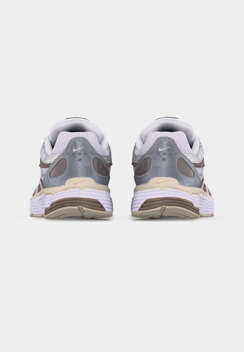 Paire de chaussures de course Nike blanches et grises vues de dos sur un fond uni gris clair.