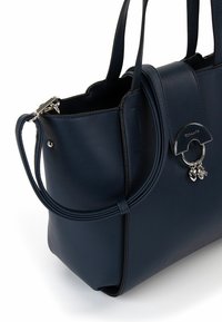 Borsa a mano in pelle blu navy con design strutturato, due manici superiori, anello in metallo argentato e charm decorativi pendenti. Texture liscia.