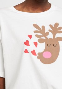 Camiseta blanca de manga corta con un reno de dibujos animados que tiene cuernos marrones, nariz rosa y corazones rojos flotando cerca. Diseño simple.