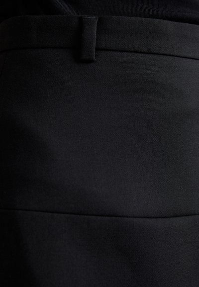 Jupe en tissu noir au toucher lisse, avec une taille visible et des détails de couture. Design minimaliste sans matériel ou accents visibles.