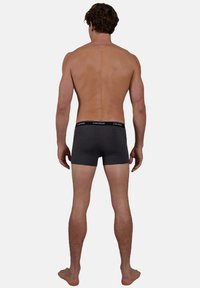 Gray cotton boxer briefs with a black waistband, viewed from the back. The design features a snug fit and smooth texture.
