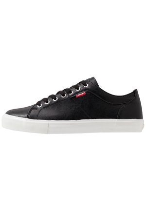 Sneaker Levi's nera a taglio basso con suola in gomma bianca, lacci neri e etichetta rossa con logo Levi's sul lato.