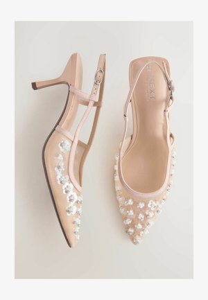 Nackte High-Heels mit spitzer Spitze, Mesh-Obermaterial, floralen Verzierungen und Knöchelriemen mit Metallschnalle.