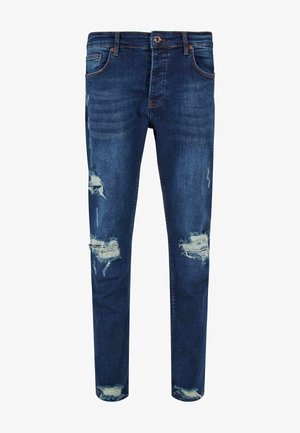 Niebieskie dżinsy o slim fit, z przetarciami i postrzępionymi krawędziami. Posiadają pięć kieszeni i zapięcie na guzik.