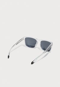 Klare plast sunglasses med mørke linser. Den klassiske designen har en vinkelrett form, gjennomsiktige armer og svarte tips på bøylene.