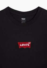 Černé bavlněné tričko s kulat�ým výstřihem, s červeně vyšitým logem Levi's v rozpoznatelném tvaru na hrudi. Vintage střih.