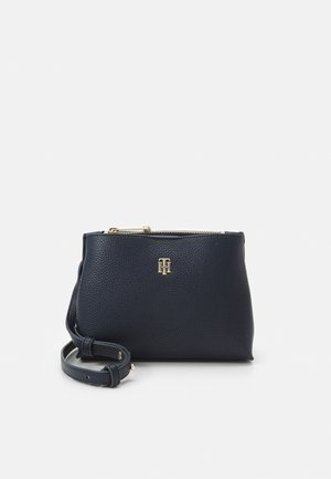 Marine læder håndtaske med kornet tekstur, lynlås lukning og justerbar rem. Har guldtonet logo på fronten og minimalistisk design.