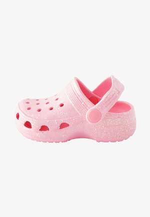 Roze rubberen klomp met een glanzende afwerking, voorzien van ventilatiegaten, een achterband en een gevlekt textuur. Ronde neus en verhoogde randen.