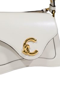Hvid læderhåndtaske med en buet klap og gulddetaljer. Har en markant guldløgo-accent og kontrastfulde sorte kantsting.