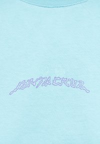 Ανοιχτό μπλε ύφασμα με κυματιστό μοβ κείμενο κεντημένο, μερικώς ορατό και αφηρημένο στο ύφος.