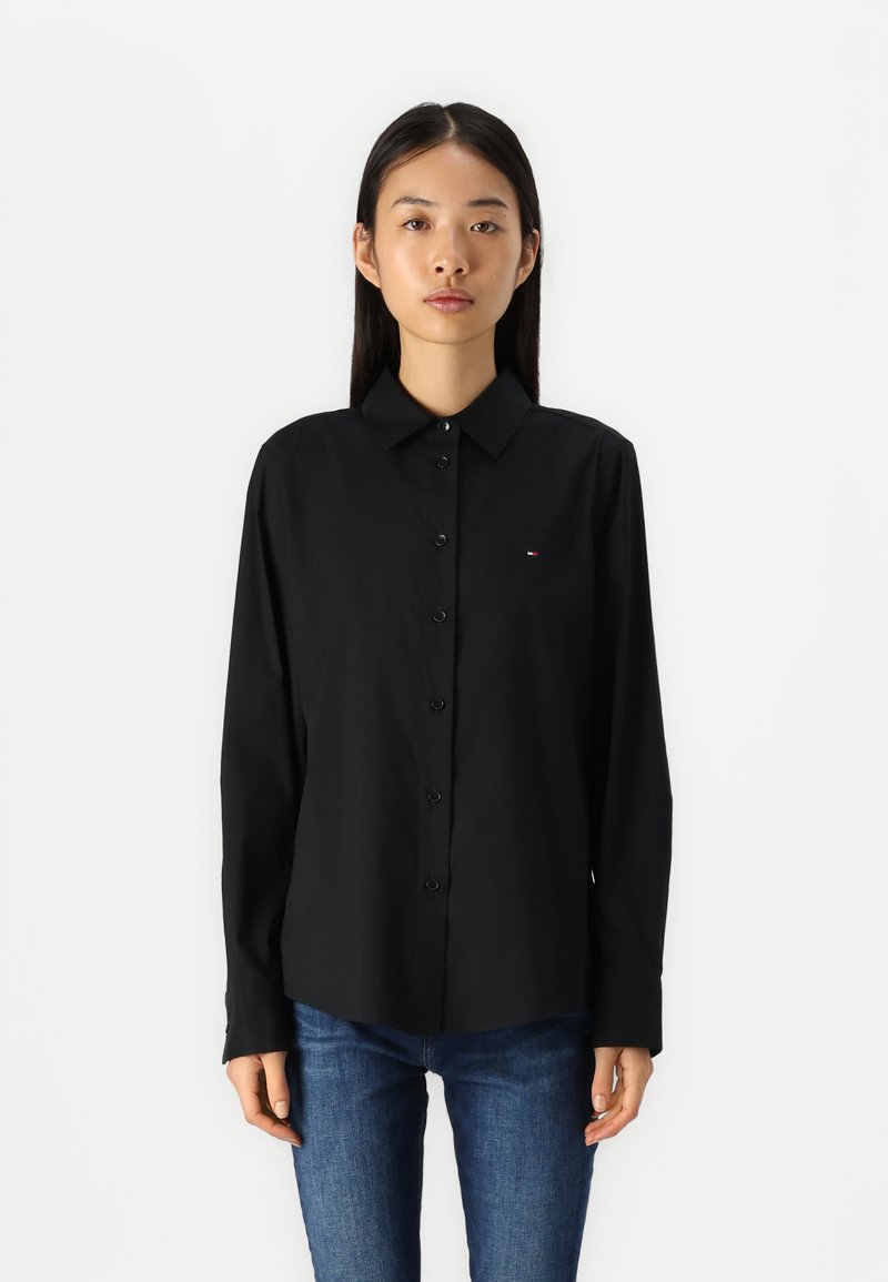 Zwarte lange mouw button-up shirt met een gestructureerde kraag, voorzien van een klein logoaccent op de borst en een gladde stoftextuur.