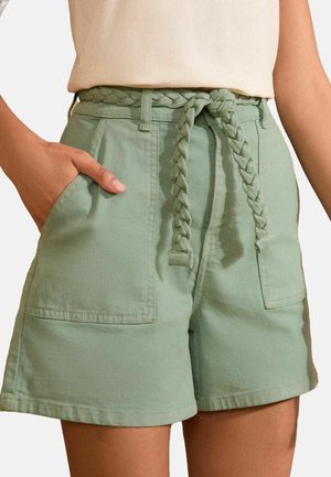Shorts vert clair en coton avec une ceinture tressée, deux poches latérales et une coupe ajustée avec des ourlets repliés.