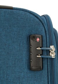 Valise en tissu bleu avec une finition texturée. Dotée d'un mécanisme de verrouillage noir avec des accents rouges et argentés, et de tirettes de fermeture éclair bleues.