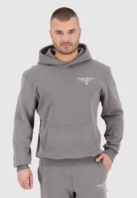 Grijze katoenen hoodie met een voorzak, ribgebreide manchetten en zoom, met witte logotekst op de linkerborst.