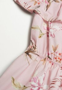 Vestido floral con tejido rosa y cinturilla elástica. El diseño incluye diversas flores, hojas y texturas suaves.