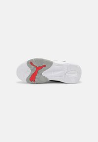 Semelle de chaussure de sport Puma présentant un motif blanc et gris, un accent rouge du logo, et desRainures texturées pour l'adhérence.