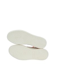 Schuhsohlen aus einem strukturierten, weißen Gummimaterial mit hexagonalem Muster, glatten Kanten und einer Markenbeschriftung in der Mitte.