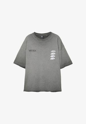 Grijze oversized T-shirt met de tekst "TRUE SELF" op de linkerborst en vier witte ooggraphics in een verticale lijn op de rechterborst.