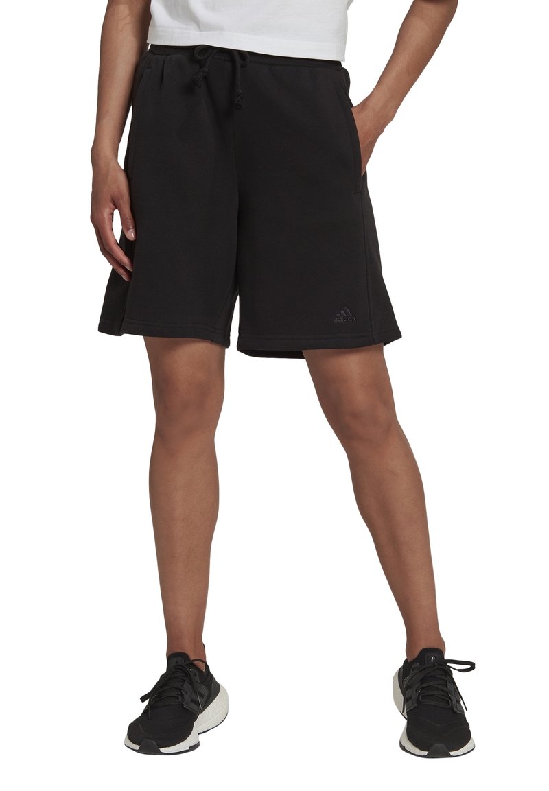 Pantalones cortos de algodón negro con un cinturilla elástica y cordón de ajuste, que cuentan con bolsillos laterales y un pequeño logo en la parte inferior de la pierna izquierda.