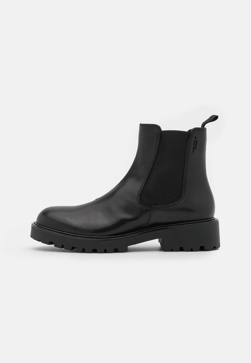 Bottines en cuir noir avec panneaux élastiques sur les côtés, bout arrondi et semelle en caoutchouc épaisse. Dotées d'une languette à l'arrière pour faciliter l'enfilage.