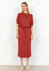 Abito rosso a due pezzi con top a maniche corte e texture a coste, abbinato a una gonna midi aderente con vita regolabile. Tessuto liscio.