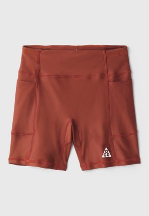 Crvene atletske kratke hlače od rastezljivog materijala, s bočnim džepovima i trokutastim logotipom na donjoj desnoj nozi. Glatka tekstura i moderni dizajn.