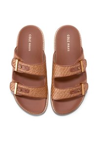 Bruna flätade sandaler med två justerbara remmar med guldfärgade spännen, slät fotbädd och märkt innersula. Platt sula design.