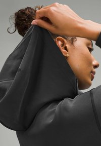 Black hoodie with a high neck and attached hood, showcasing smooth fabric, visible stitching, and a snug fit around the shoulders.