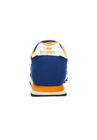 Blå och orange New Balance-sneaker sedd bakifrån, med logotyp på vit hälflik och orange sula.