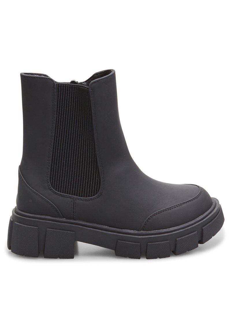 Botines negros hasta el tobillo hechos de material liso, con paneles laterales elásticos, suelas gruesas y un diseño de punta redonda. Acentos texturizados en los lados.