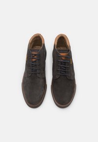 Dunkelgraue Wildlederschuhe mit glatter Oberfläche, braunen Lederakzenten und schwarzen Schnürsenkeln. Abgerundete Zehenpartie und kontrastierende Nahtdetails.