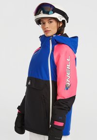 Blauw, roze en zwart skijas met ritssluiting aan de voorkant, capuchon, grote voorkantzak en logodetails op de mouw. Voorzien van geïsoleerde stof.