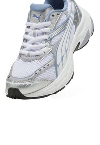 White and silver athletic shoe with mesh panels, rounded toe, blue accents, lace-up closure, and textured sole for grip.