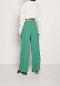 Pantaloni verdi a gamba larga realizzati in un tessuto morbido e leggero, con una vita elastica e un fit rilassato per il massimo del comfort.