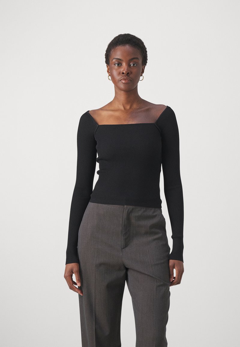 Haut noir à manches longues côtelé avec un décolleté carré, associé à un pantalon gris. Le tissu a une texture lisse avec un design ajusté.