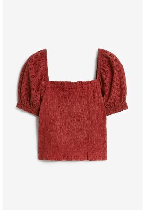 Blouse courte smockée rouge rouille avec encolure carrée et manches bouffantes en dentelle ajourée.