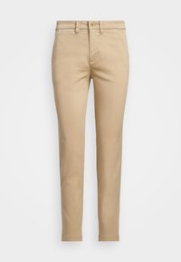 Béžové bavlnené nohavice chinos so slim fit strihom, s predným zapínaním na gombík, bočnými vreckami a prešitými okrajmi. Hladká textura a jednoduchý dizajn.