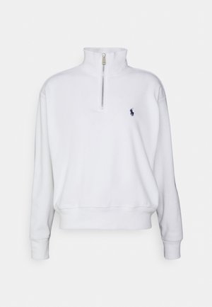 Witte trui met lange mouwen, halve ritssluiting aan de kraag en klein marineblauw geborduurd logo op de linkerborst, geribbelde boorden en zoom.