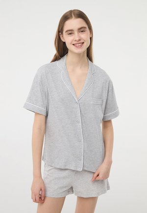 Completo pigiama in cotone grigio a maniche corte con piping bianco e tasca sulla maglietta. I pantaloni sono anch'essi grigi e hanno una vestibilità comoda.
