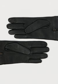 Luvas de couro preto com cinco dedos, apresentando uma textura suave e um pequeno fecho de zíper no pulso para fácil colocação.