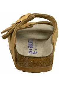 Sandalo in suede marrone con suola in sughero, dotato di una fascia larga e dettaglio con fibbia; soletta testurizzata con taglie e marchio in blu.