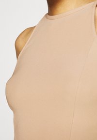 Top a maniche lunghe in tinta unita con un colletto alto, design senza maniche e bordi senza cuciture per una vestibilità liscia. Tessuto leggero e elasticizzato.