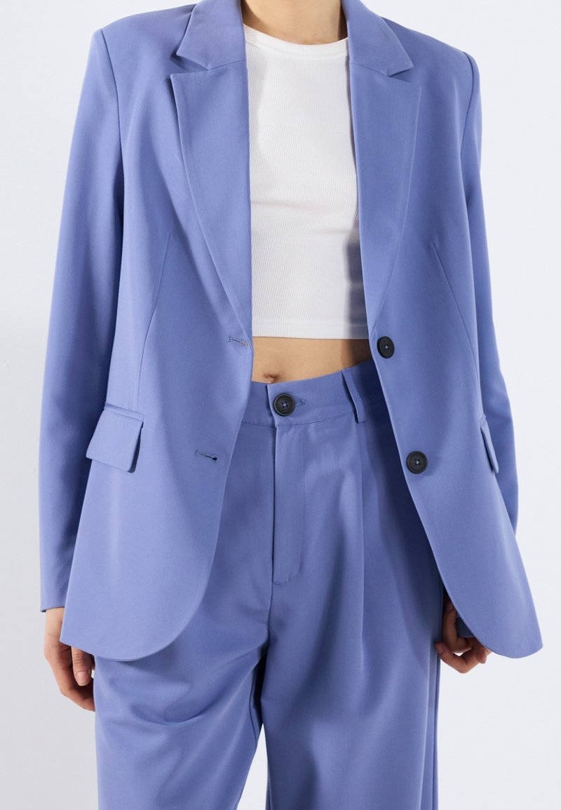 Lichtpaarse blazer van gladde stof, met een geknipte kraag, twee knopen en een getailleerde pasvorm met klepzakken. Gecombineerd met bijpassende broek.