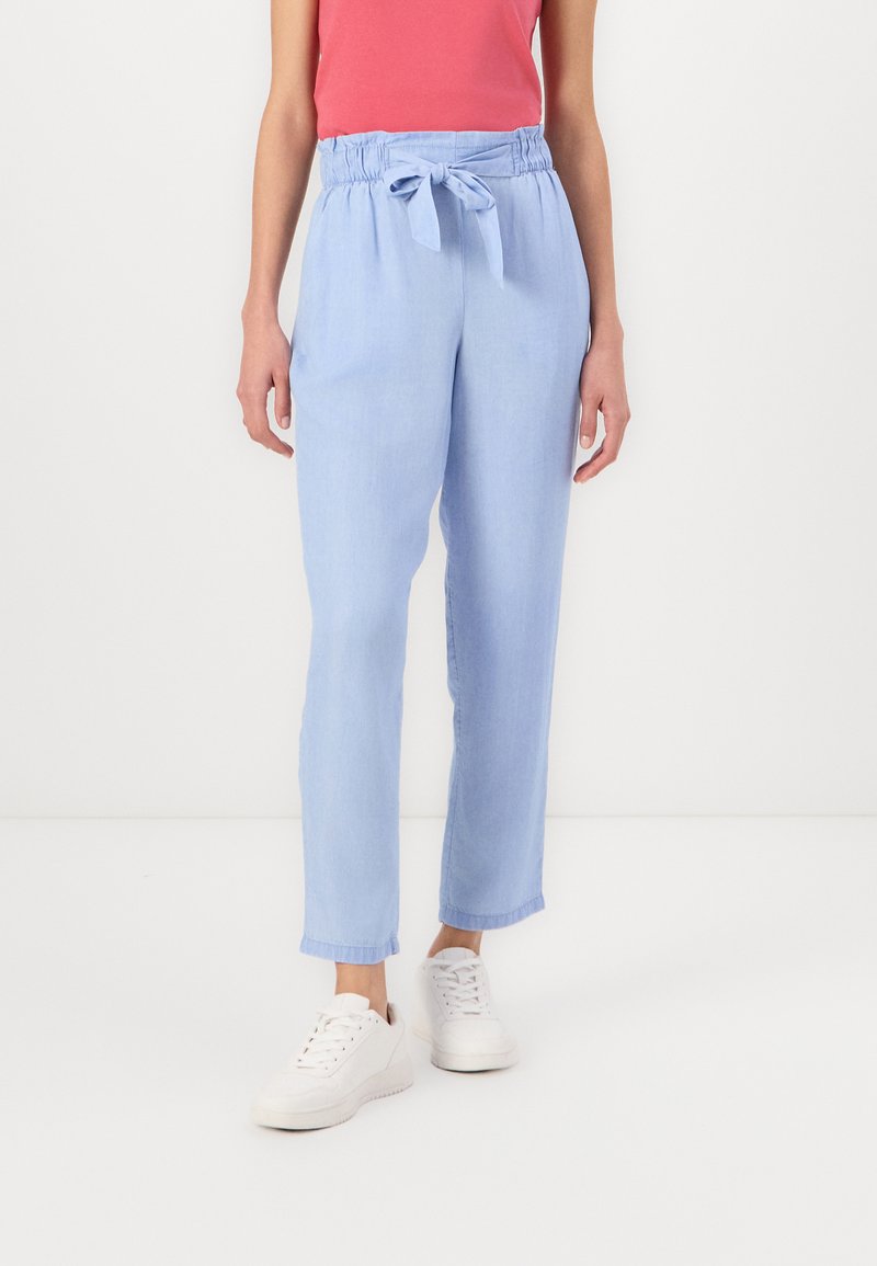 Pantalones de color azul claro con un corte relajado, cintura elástica y cinturón de tela. Presentan dobladillos acampanados y una textura suave. Combinados con zapatillas blancas.