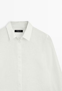 Camicia bianca in lino a manica lunga con bottoni, colletto classico e texture sottile, etichettata "Massimo Dutti".