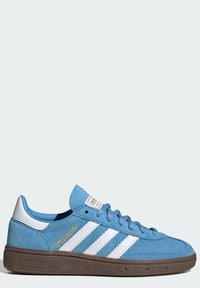 Modre semišne superge z belim tridelnim dizajnom, zlatim logotipom in rjavim gumijastim podplatom, ki vsebuje teksturiran vzorec za oprijem.