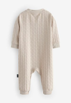 Beige pletený dětský overal s texturovaným vzorem, dlouhými rukávy a elastickými manžetami. Obsahuje kulatý výstřih a patentky na spodní části.