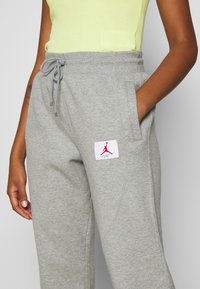 Grijze joggingbroek met een verstelbare tailleband, voorzien van een rode Jordan-logopatch. Gemaakt van zachte, gestructureerde stof, met zijzakken.